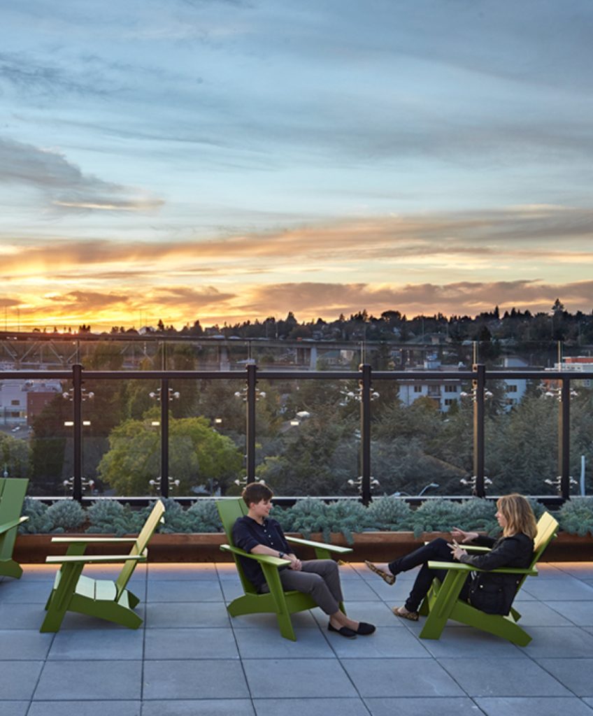Two people sitting in chairs on rooftop deck
