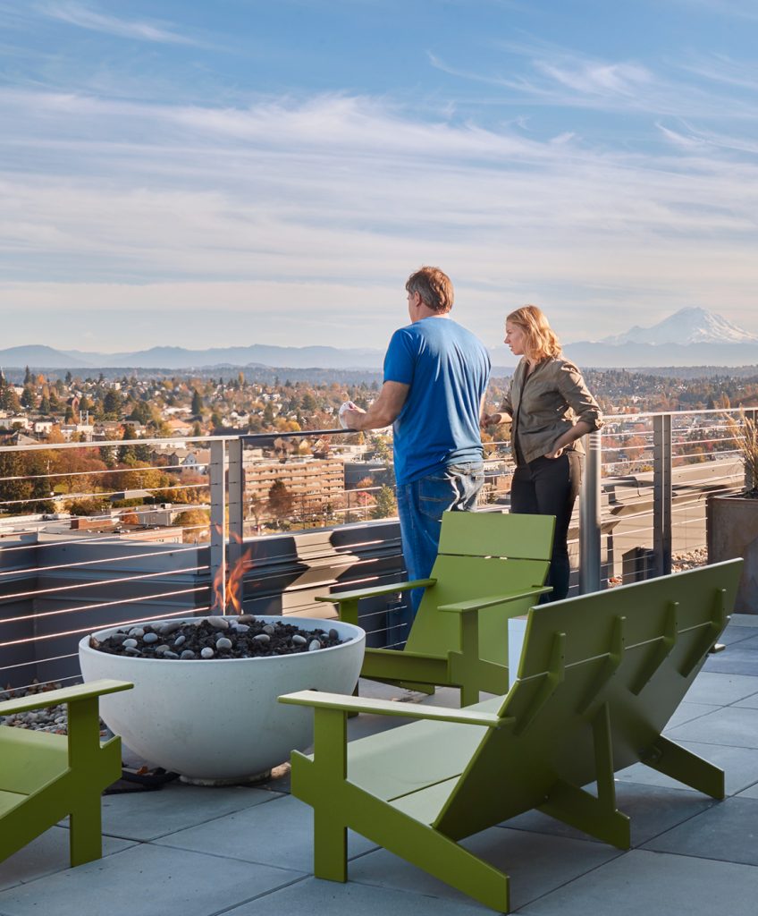 Two people standing on rooftop deck looking at the view